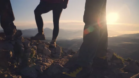 Low angle, hikers admire the view at the top of the mountain at sunrise Stock Footage 140825807