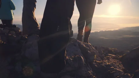 Low angle, hikers admire the view at the top of the mountain at sunrise Stock Footage 140826305