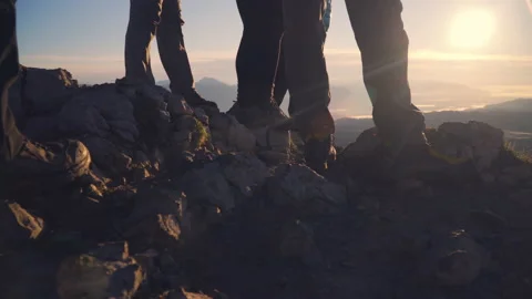 Low angle, hikers admire the view at the top of the mountain at sunrise Stock Footage 140826512