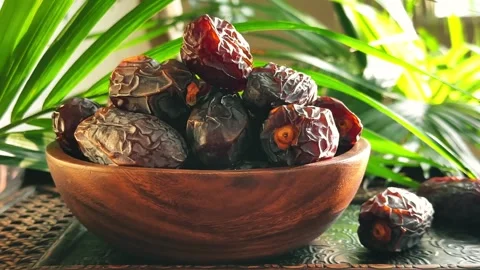 Low angle horizontal camera move past date fruit in wooden bowl with palm l.. Stock Footage 339080903