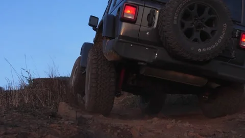Low angle of an off Jeep Wrangler driving through difficult road in the Stock Footage 241963805