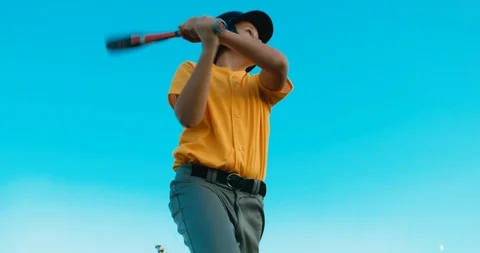LOW ANGLE kid boy batter baseball player hits a ball against blue sky Stock Footage 96710090