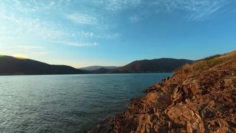 Low-Angle Lake Shot with Red Earth Shore – Calm Water, Autumn Evening Vídeos de archivo 330989030
