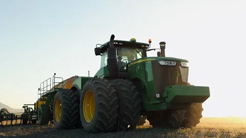Low angle: Large green tractor tows seeding implement in wheat field Stock Footage 310651371