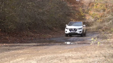 Low angle left slow motion of a suv white car driving into water on a dirt p Stock Footage 123642691