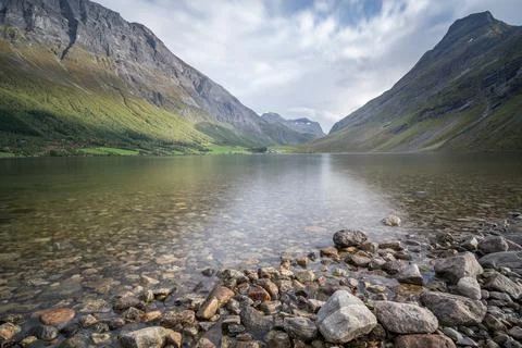 Low angle long exposure of Norwegian lake with dramatic mountains around and a Stock Photos