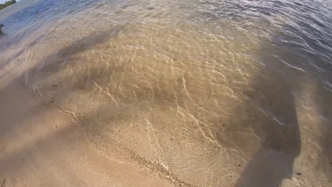 Low angle look down on ground view at beach sandy side with ripple water poundin Stock Footage 253461624