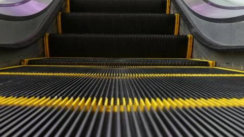 Low angle looped perspective view of modern escalator stairs. Automated eleva Stock Photos