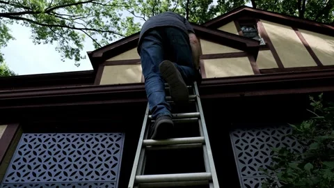 Low angle of Man climbing a ladder to clean his gutter Stock Footage 337603807