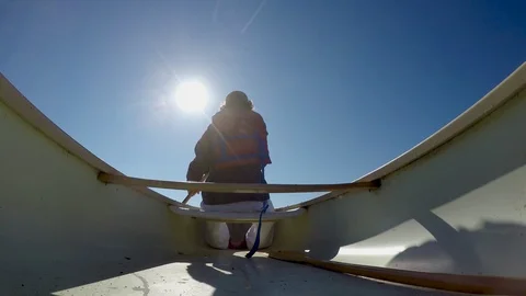Low angle of a man paddling a canoe directly into the sun Stock Footage 90088826
