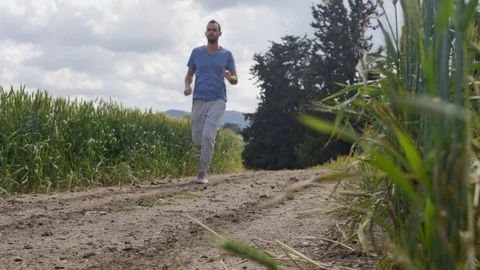 Low angle - man runs through dirt road in a countryside area. Slow motion Stock Footage 107271184