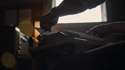 Low angle of a man typing at a typewriter, he pulls the paper out and checks Stock Footage 97870177