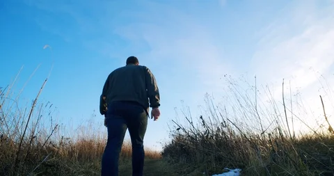 Low Angle of Man Walking Into Sunset Stock Footage 122221312