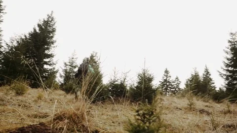 Low angle of a man wearing a backpack walking up hill Vídeo Stock 128923303