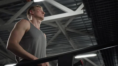 Low Angle of Man Wiping Sweat and Drinking Water after Treadmill Workout Stock Footage 339880646