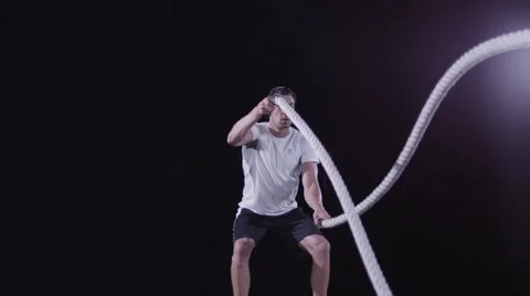 Low angle of a man working out using battle ropes - Isolated on Black Stock Footage 63808173