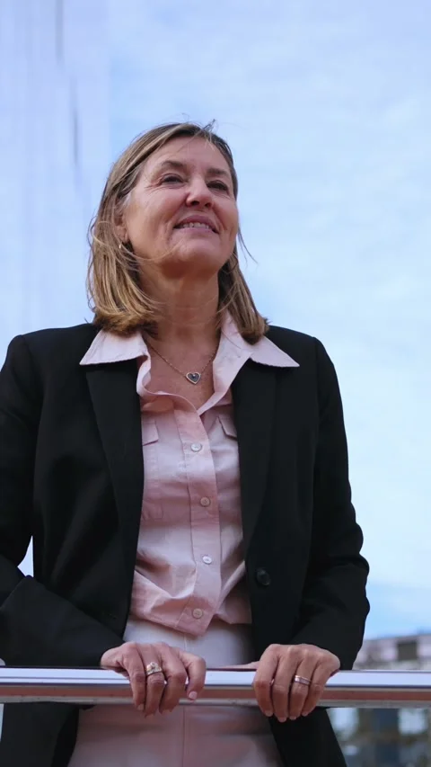 Low angle mature blonde formal business woman with cheerful expression leaning Stock Footage 277121568