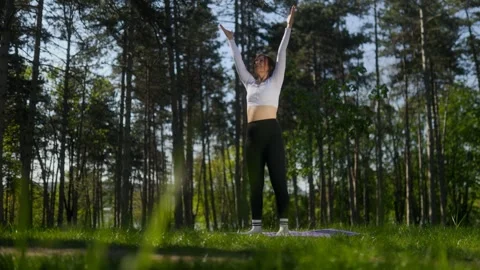 Low angle of mature woman Doing a fitness raising arms for fitness in forest Stock Footage 335191560