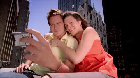 Low angle medium shot man and woman sitting on rooftop taking their picture with Stock Footage 46260374