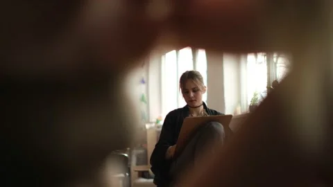 Low angle medium shot of a woman artist painting sketching in studio Stock Footage 233625341