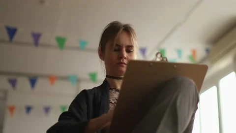 Low angle medium shot of a woman artist painting sketching in studio Stock Footage 233625397