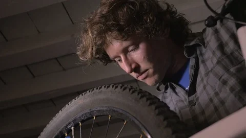 Low angle of a millennial man bike mechanic working on a bicycle wheel Stock Footage 69907677