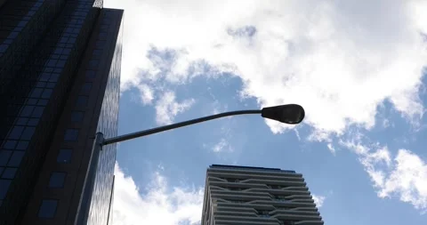 Low angle of modern towers and streetlight under moving clouds in the city Stock Footage 320017238
