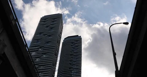 Low angle of modern towers and streetlight under moving clouds in the city Stock Footage 320017241