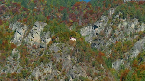 Low Angle of Mountain Hermitage Built into Cliff Surrounded by Autumn Trees Stock Footage 320046804