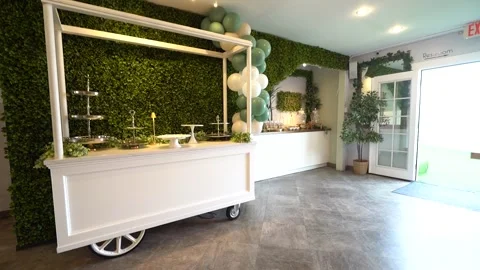 Low angle move past a white dessert cart and green hedge wall Stock Footage 345555557