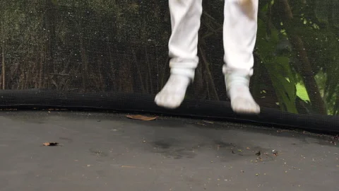 Low Angle of Muddy Child Jumping on Trampoline Surrounded by Nature Stock Footage 291413928