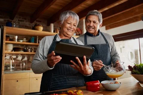 Low angle of Multi-cultural elderly couple smiling, using tablet to research Stock Photos