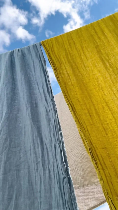 Low angle of natural linen fabrics drying outdoors with a serene sky backdrop Stock Footage 344301516