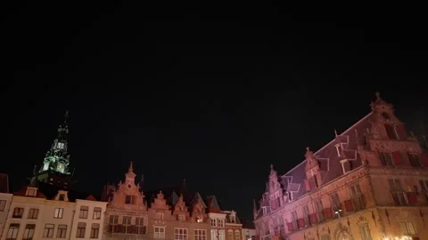 Low-angle night view of historic Grote Markt buildings and clock tower in Stock Footage 332615002