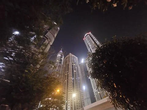 Low-angle night view of illuminated modern skyscrapers soaring into the dark sky Photos