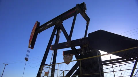 Low angle of oil derrick pumping against blue sky. Stock-Footage 46733818