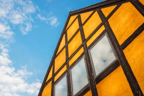 Low angle of an orange house with timber framing and cloudy sky Stock Photos