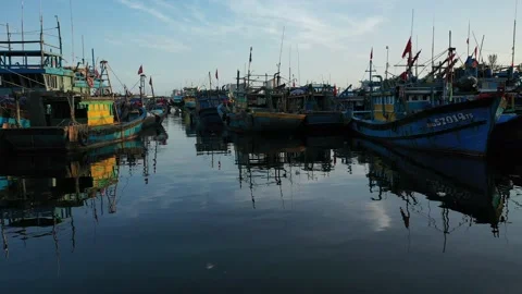 Low angle pan across fishing boats anchoring at sunset Stock Footage 147984487