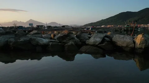 Low angle pan across shore of fishing village bay at sunset Stock Footage 147983750
