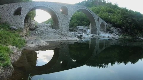 Low-Angle Pan of Devil’s Bridge With Mirror Reflection in Arda River Stock Footage 321372694