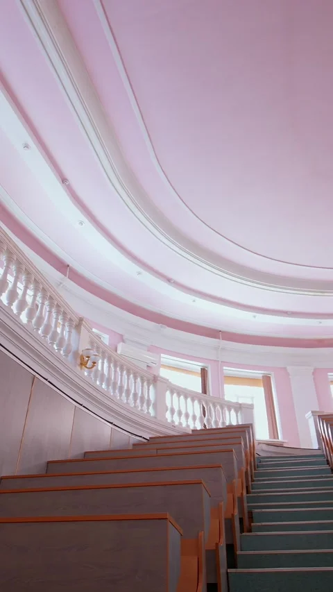 Low angle pan of empty classical lecture hall with pink walls and white arc.. Video stock 337481715