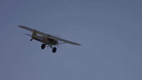 Low angle pan of Super Cub plane making a right turn while flying at evening Stock Footage 252382795