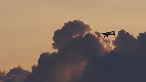 Low angle pan of Super Cub plane flying at sunset adjacent nimbus clouds Stock Footage 252383119