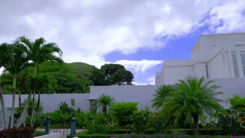Low angle panning shot of Laie Hawaii Temple surrounded by flowers and greenery. Stock Footage 273539675