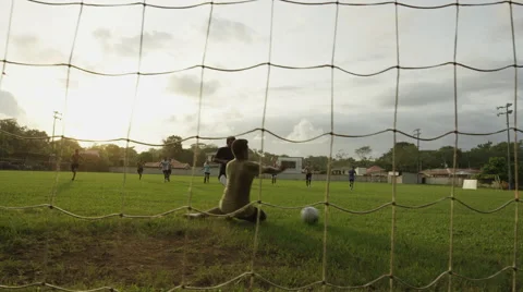 Low angle panning wide shot of soccer player scoring goal and cheering / Stock Footage