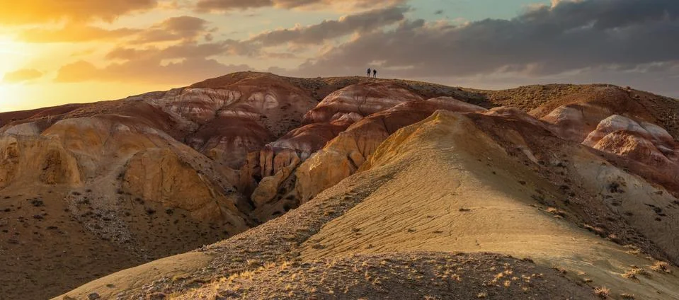 Low angle panoramic shot of two tiny figures on top of massive red mountain i Foto stock