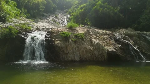 Low angle parallax of Quebrada Valencia waterfall cascading into emerald pool Stock Footage 337391670