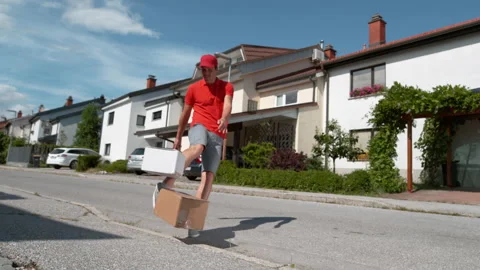 LOW ANGLE: Parcel delivery guy drop kicks a package into someone's driveway. Stock Footage 140036964