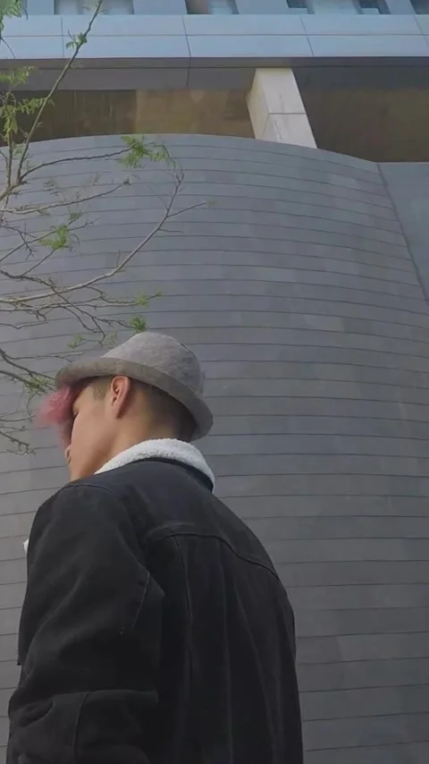 Low-angle perspective of a cool young man with dyed hair walking through a Stockbeeldmateriaal 344786531