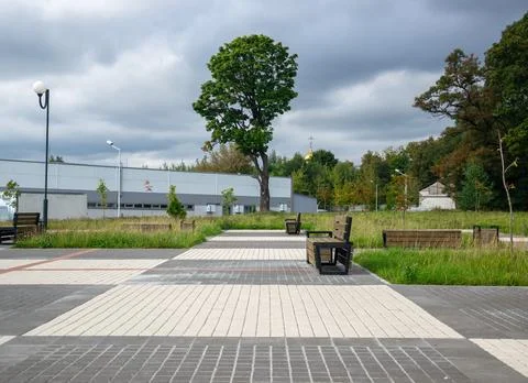 Low angle perspective of empty wooden benches and paved tile pathway Fotos de archivo